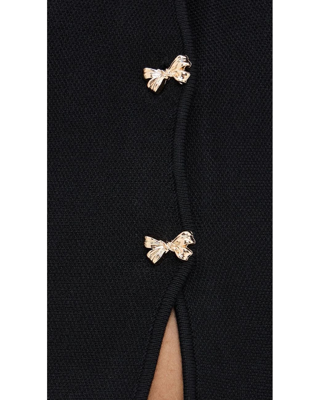 Close-up detail of the Idah Cardigan featuring gold-tone bow front buttons on black knit fabric.