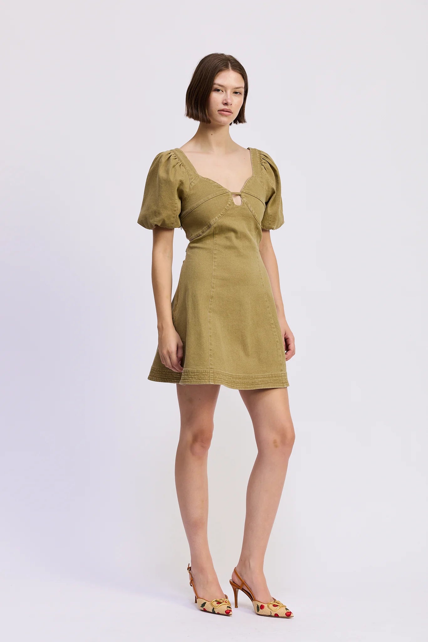 Angled front view of the Isabelle Mini Dress in olive green with puff sleeves, structured fitted bodice, sweetheart neckline, and A-line mini silhouette.