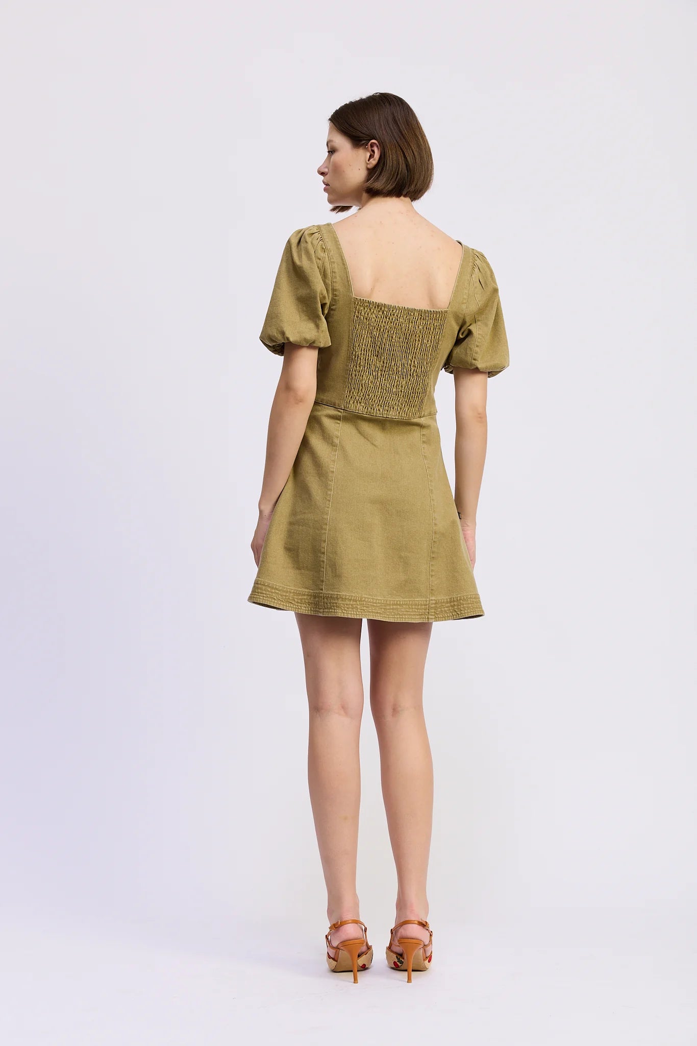Back view of the Isabelle Mini Dress in olive green showcasing the smocked back bodice, puff sleeves, and flared A-line mini skirt.