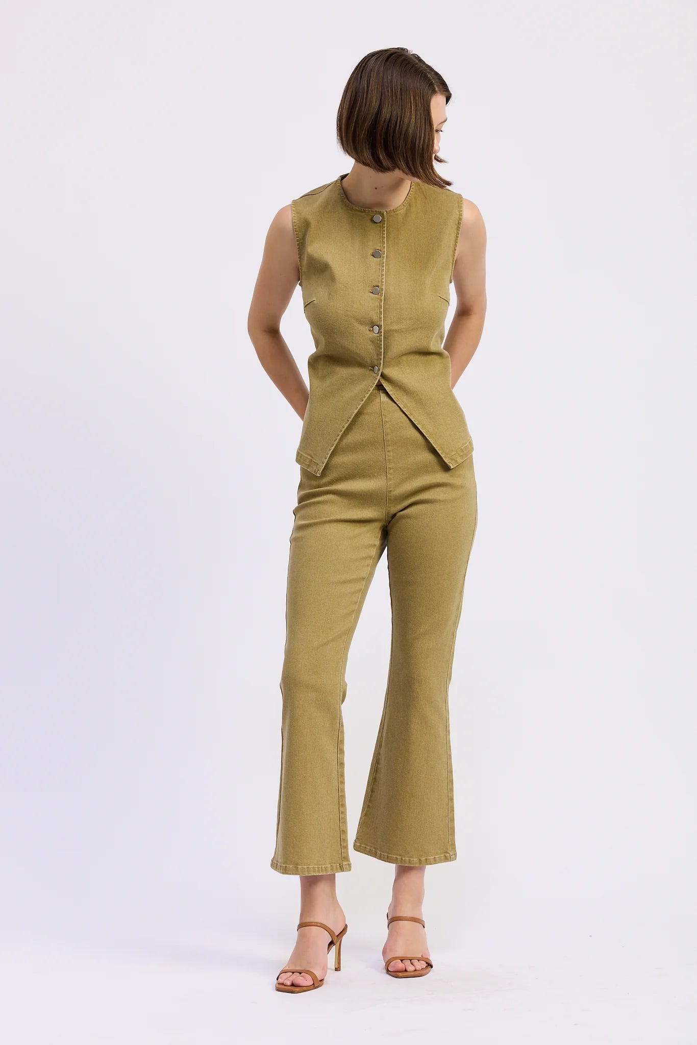 Model wearing the olive Isabelle Vest Top styled with matching high-waisted flare pants and heels.