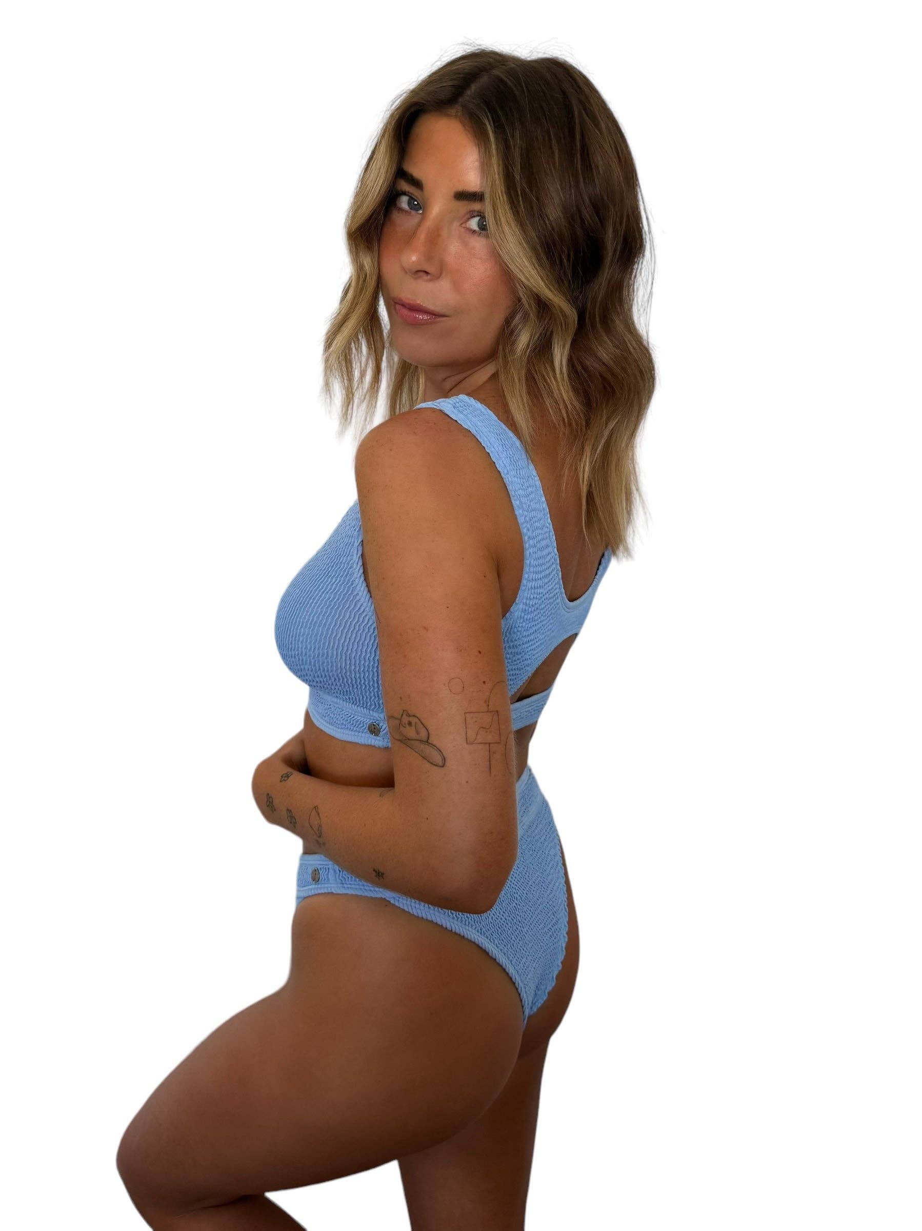 Model wearing the Janelle Bottom in Orchid, a high-waisted ribbed bikini bottom with cheeky coverage, paired with the matching Alix Top.