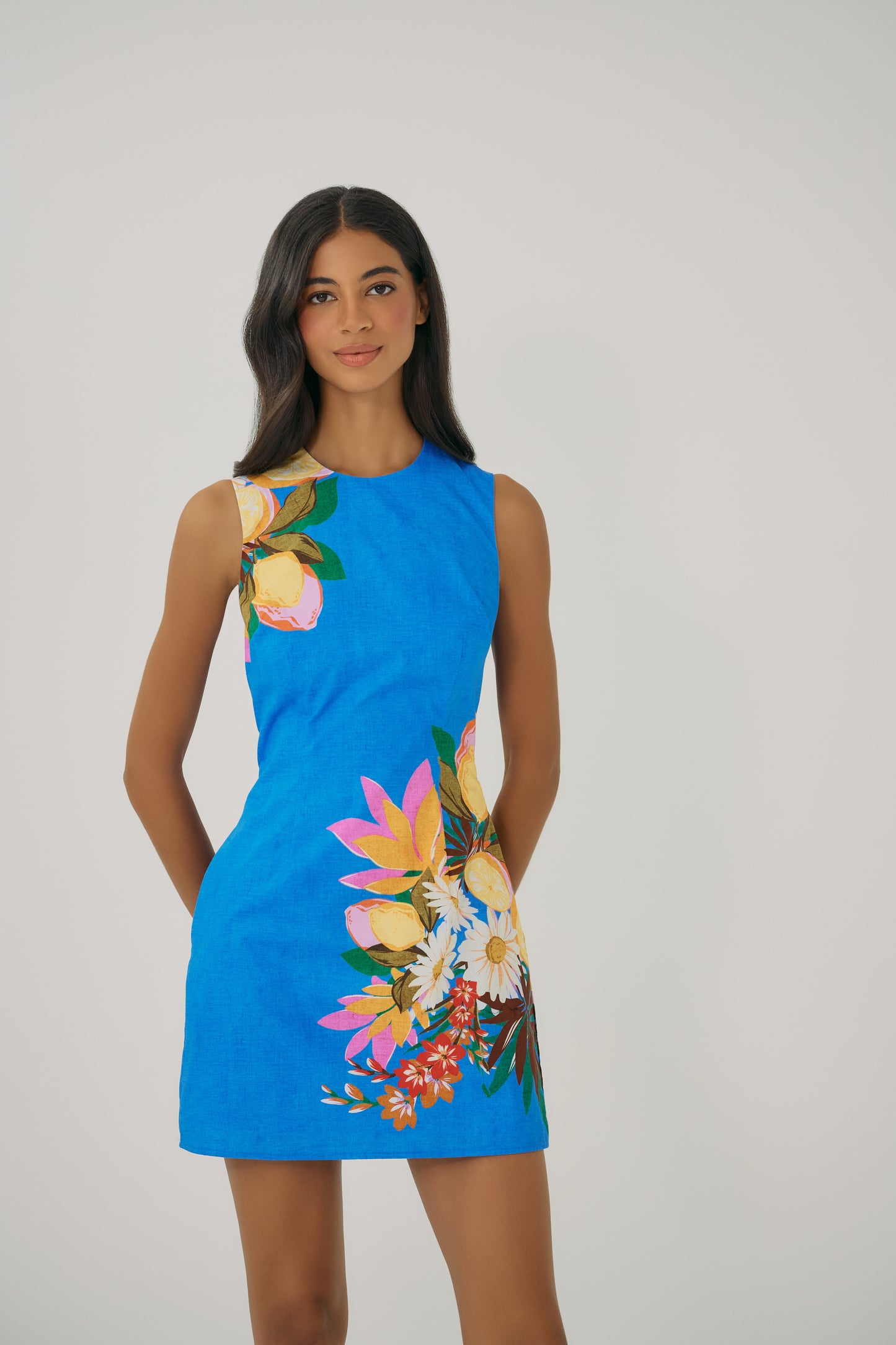 Close-up of Janesta dress showing vibrant floral placement print on blue fabric with clean sleeveless neckline