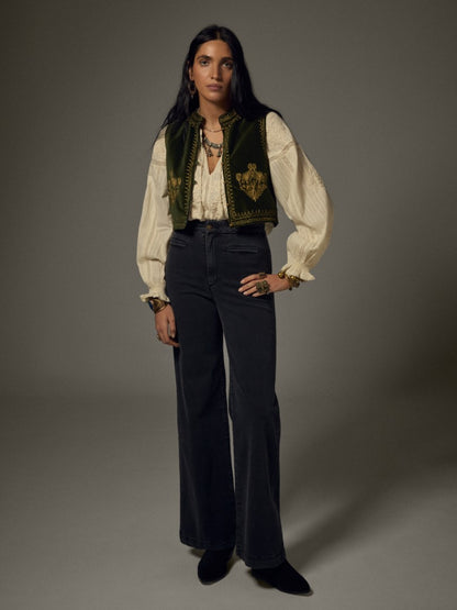 Model wearing the Maison Hotel Jimmy Vest in Hendrix Green layered over a cream blouse with dark trousers.