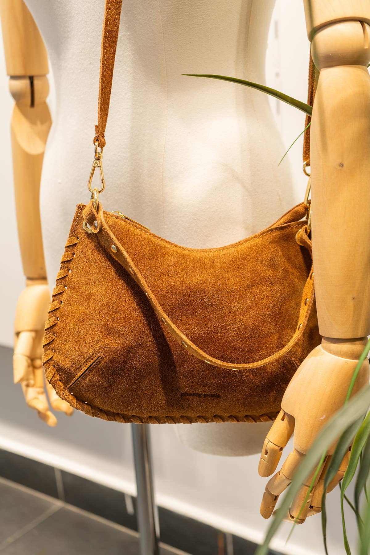 Joëlle camel suede bag displayed on a mannequin with its adjustable shoulder strap attached.