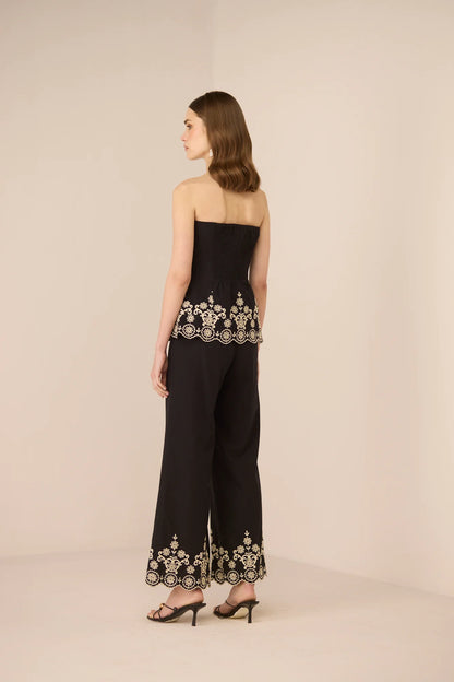 Back view of the Kaia Trousers in black, featuring embroidered scalloped hems and a clean straight-leg fit.
