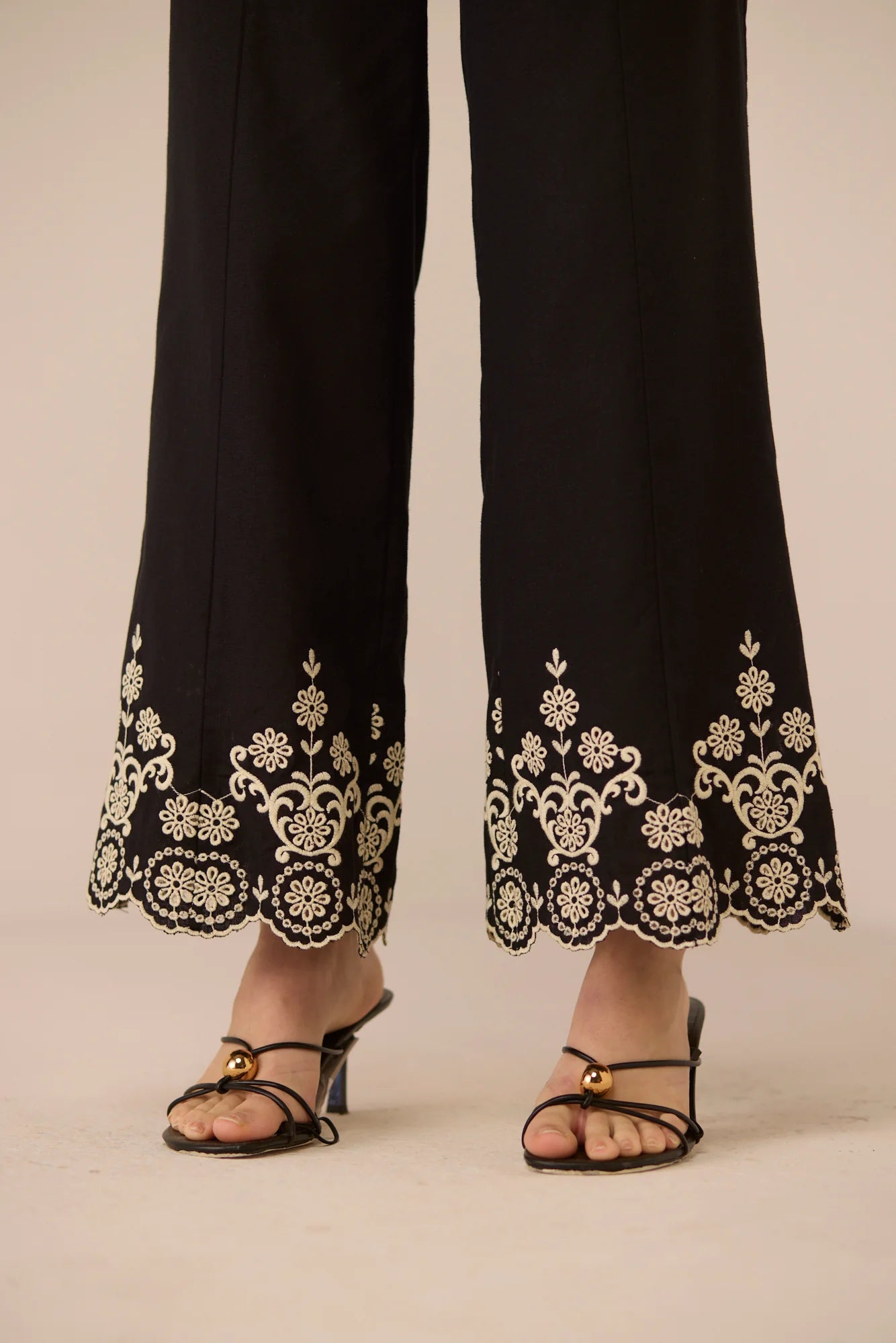 Close-up of the Kaia Trousers hem, showing detailed contrast embroidery and a soft scalloped edge.