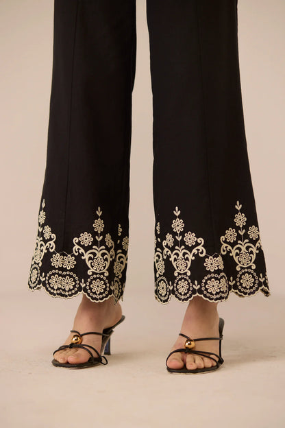 Close-up of the Kaia Trousers hem, showing detailed contrast embroidery and a soft scalloped edge.
