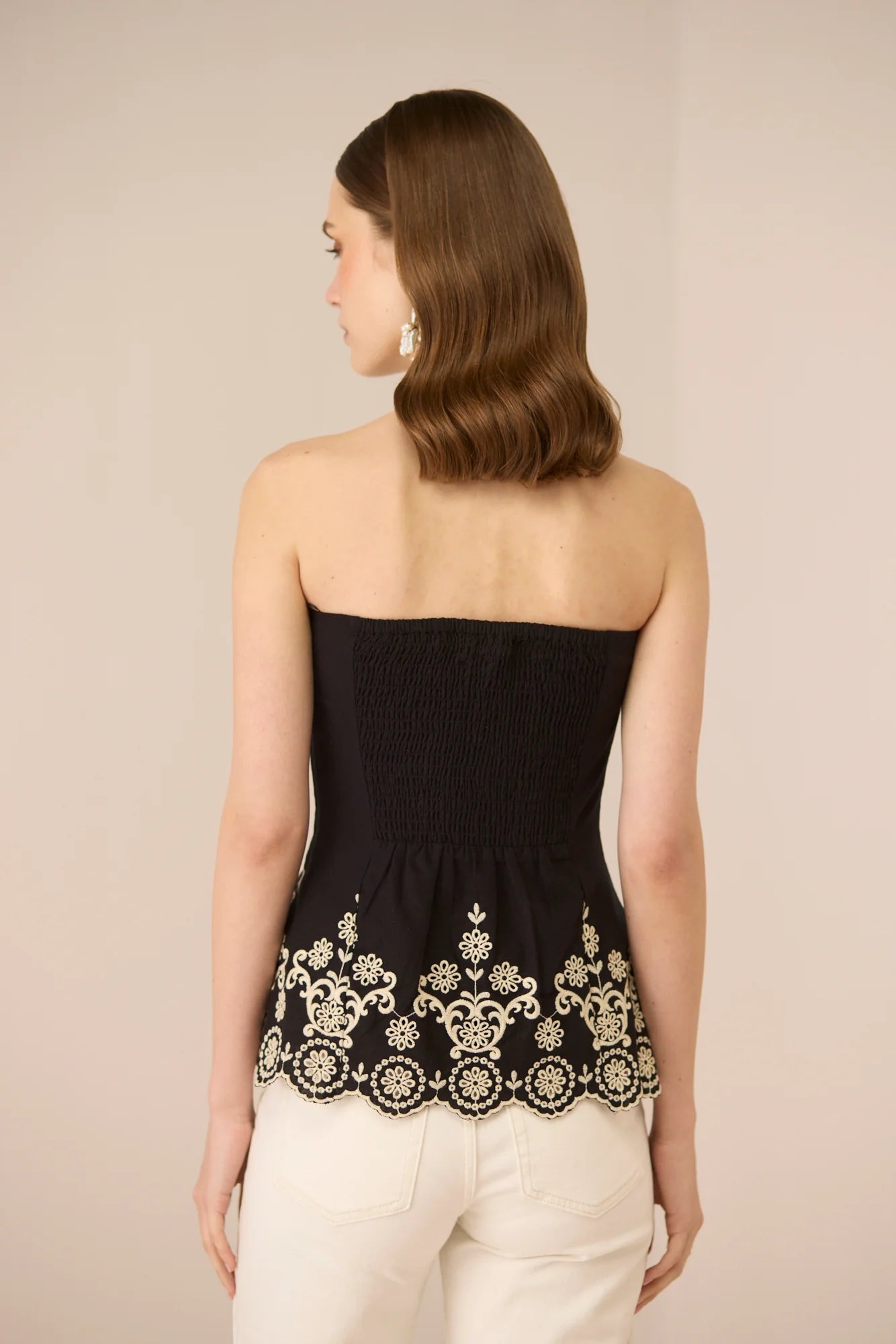 Back detail of the Kaia Tube Top in black, featuring a strapless silhouette and embroidered scalloped hem.