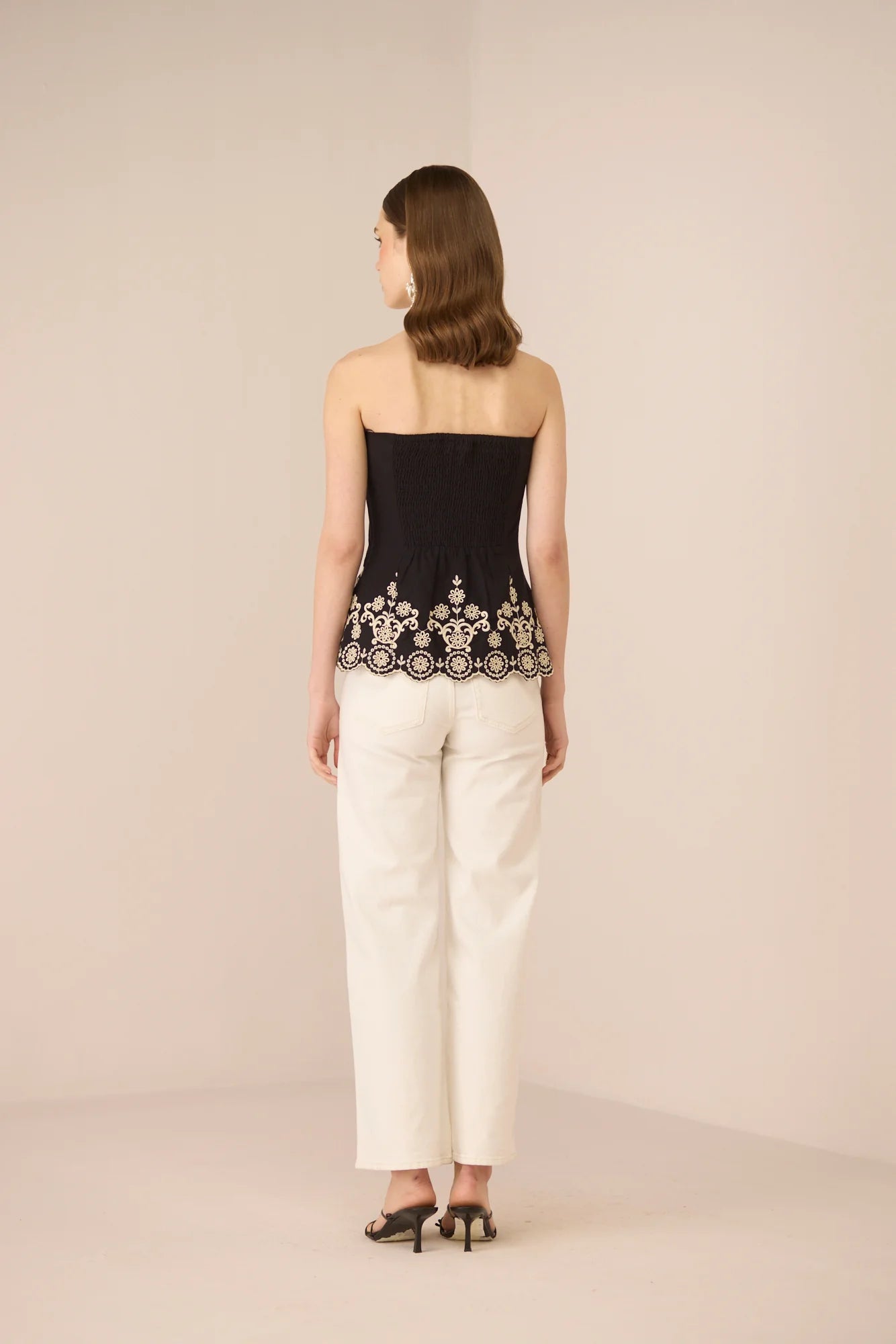 Back view of the Kaia Tube Top in black styled with white trousers.