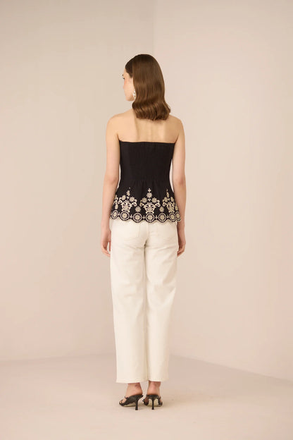 Back view of the Kaia Tube Top in black styled with white trousers.