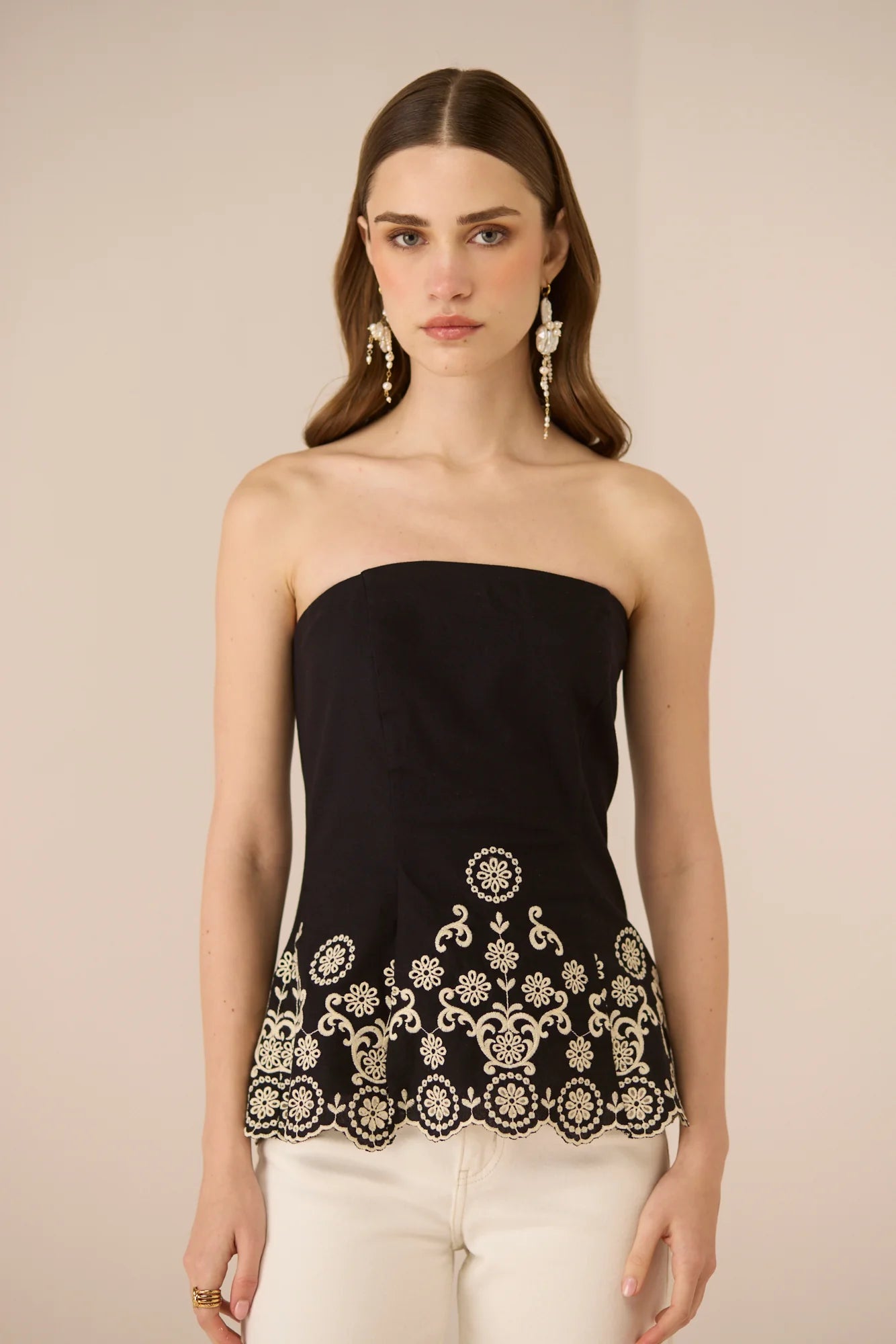 Front detail of the Kaia Tube Top in black, featuring contrast embroidery and a scalloped hem.