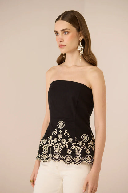 Side view of the Kaia Tube Top in black with intricate contrast embroidery along the hem.