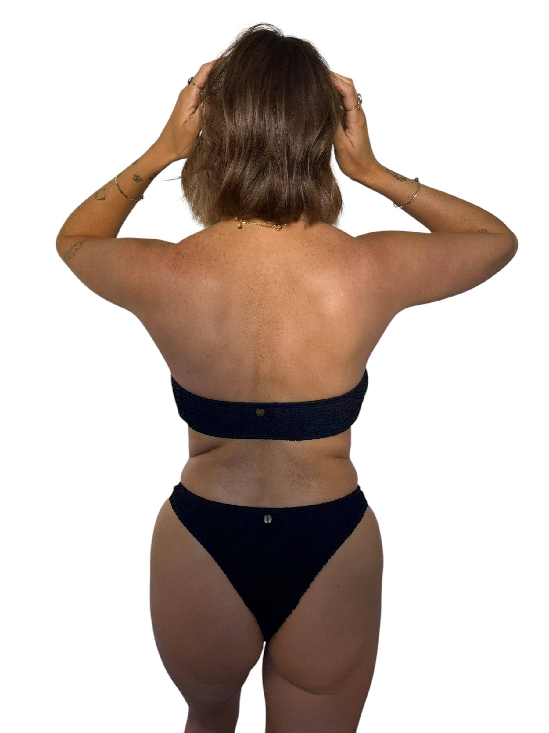 Back view of model wearing the Kayla strapless bikini top in Midnight with matching black swim bottoms.