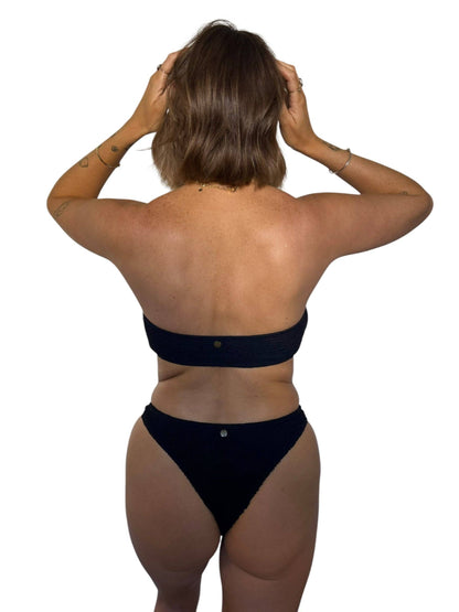 Back view of model wearing the Kayla strapless bikini top in Midnight with matching black swim bottoms.