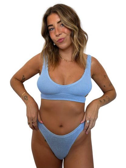 Model wearing the Kiera Top in Orchid, a light blue ribbed swim top with wide straps and matching bikini bottom.