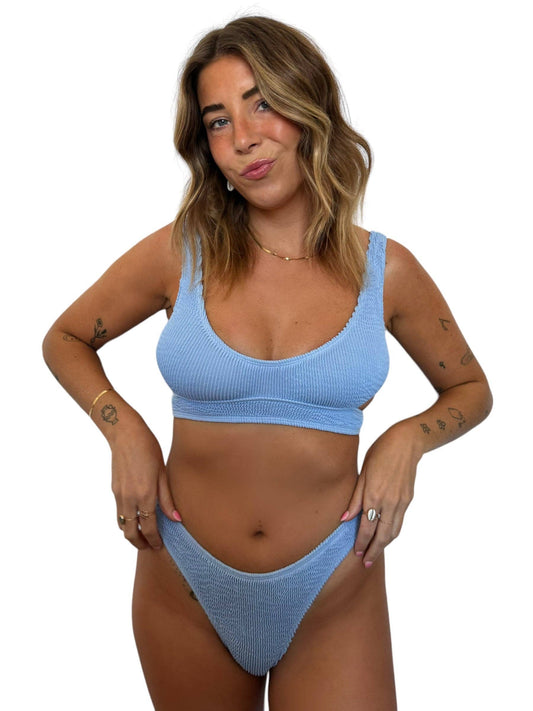 Model wearing the Kiera Top in Orchid, a light blue ribbed swim top with wide straps and matching bikini bottom.