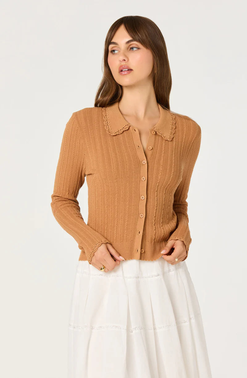 Model wearing the Kristen Cardigan in nutmeg brown ribbed knit with a scalloped crochet collar and button-front detail paired with a white midi skirt.