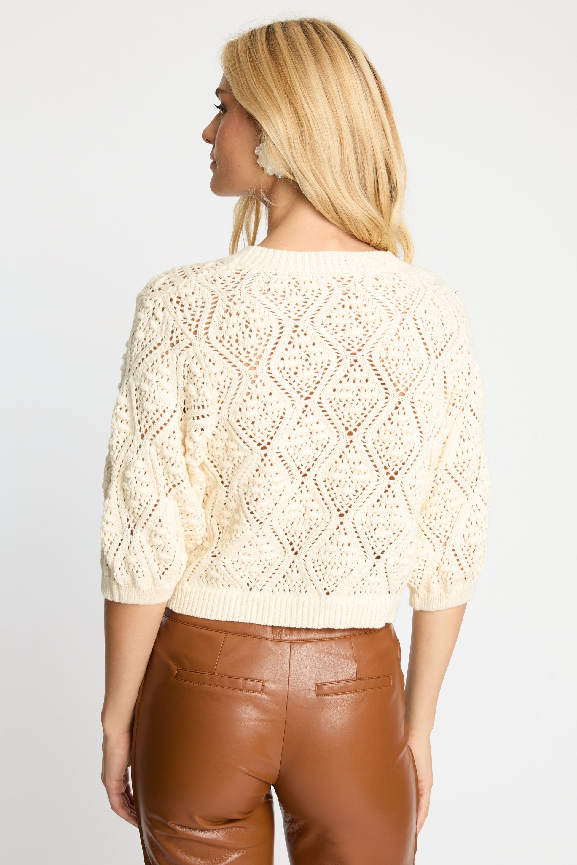 Back view of the Layla Sweater in cream displaying the openwork diamond knit design, ribbed hem, and puffed sleeves.