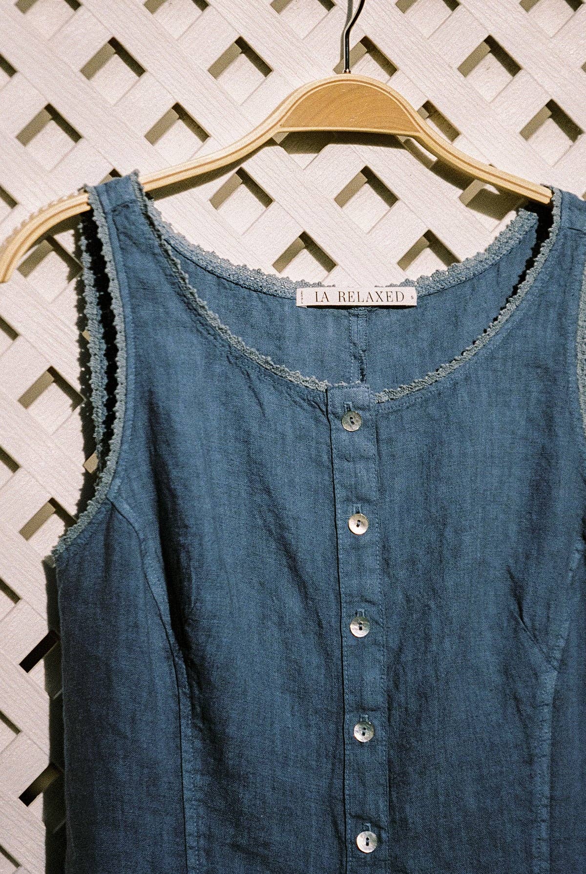 Close-up of The Linen Pinafore in Blueberry highlighting the textured linen fabric and mother-of-pearl buttons.