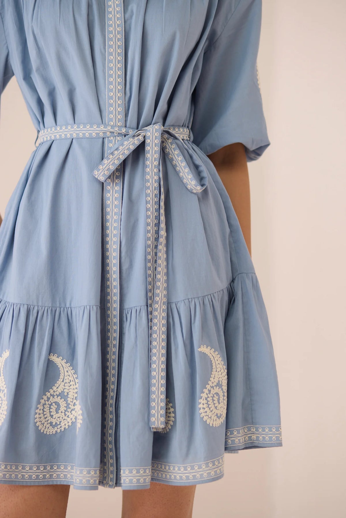 Close-up of the Lizzie Mini Dress in Dusty Blue showing the matching embroidered belt and gathered waist