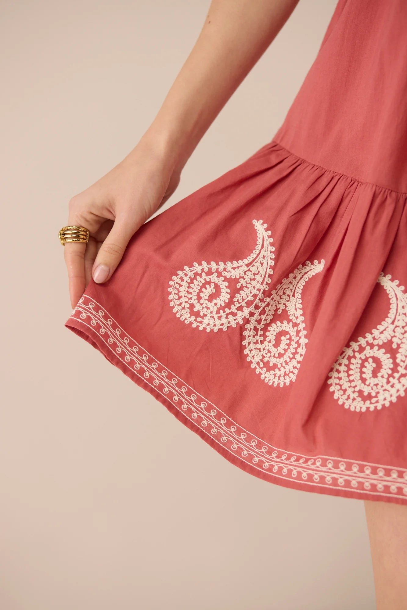 Close-up detail of the Lizzie Mini Dress showing cream paisley embroidery and embroidered border along the dusty rose hem.