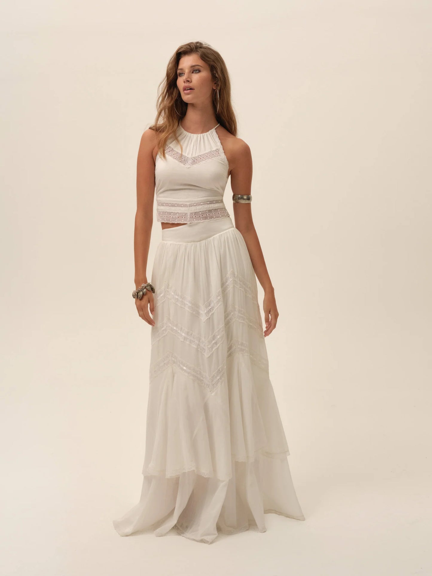 Model wearing the Lou Scarf Top in ivory with a halter neckline, embroidered detailing, and matching flowing maxi skirt front view.