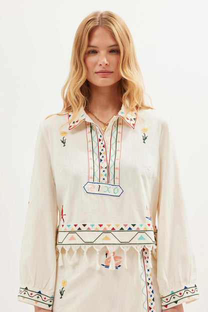 Model wearing the Ludmilla Top in Wildling Embroidery Cream featuring colorful embroidery, tassel fringe trim, long sleeves, and a relaxed cotton silhouette