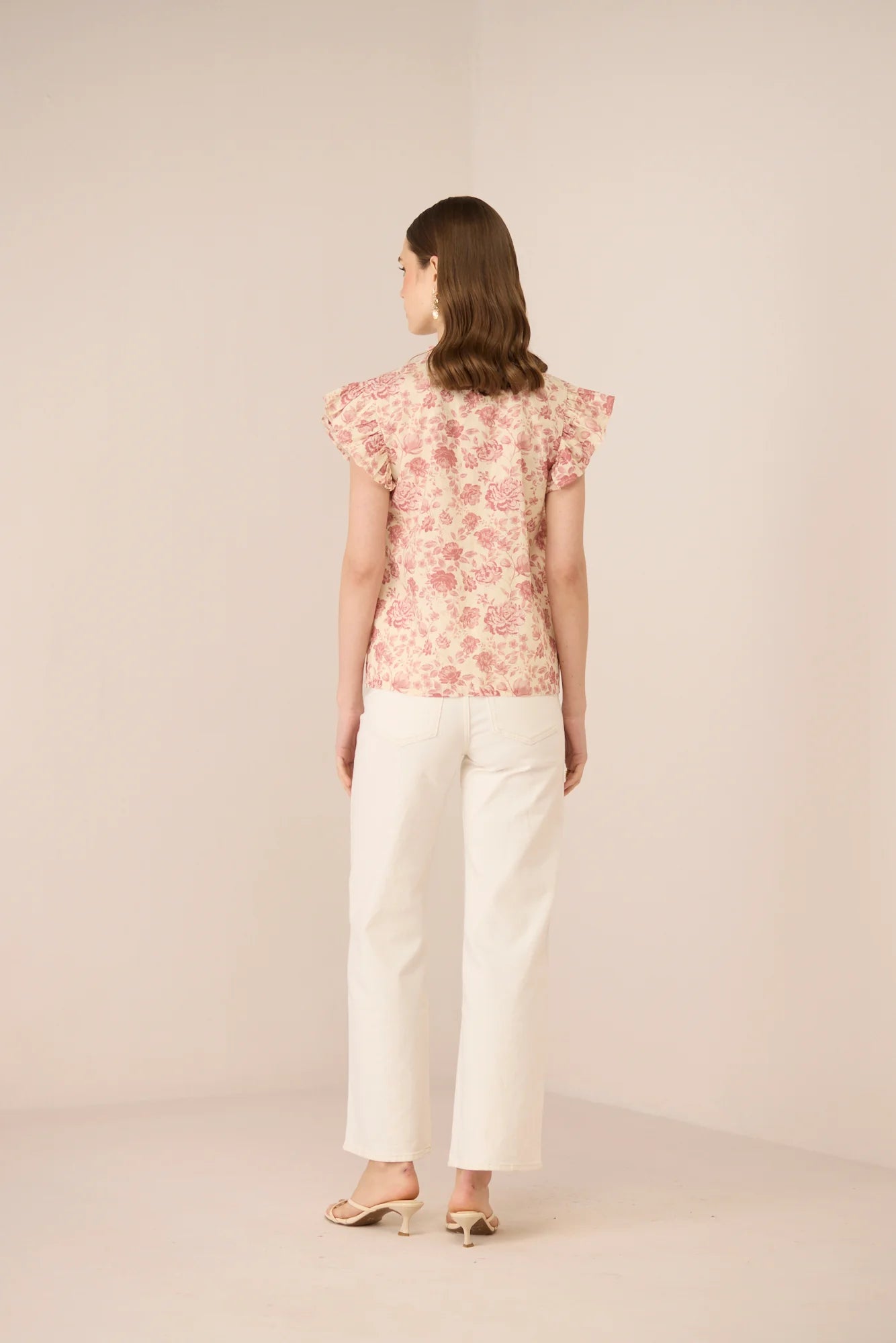 Back view of the Madison Blouse styled with white trousers, showing the easy silhouette and floral print.