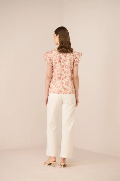 Back view of the Madison Blouse styled with white trousers, showing the easy silhouette and floral print.