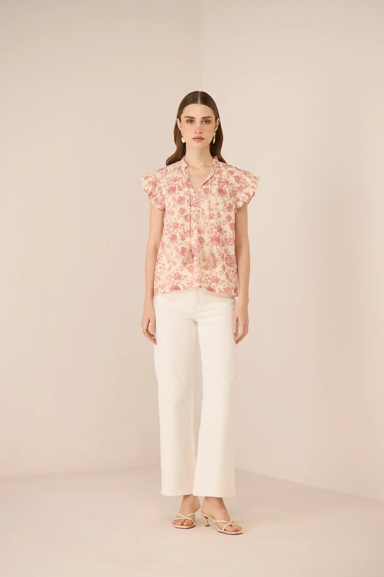 Model wearing the Madison Blouse in a soft floral print with white trousers, shown from the front.