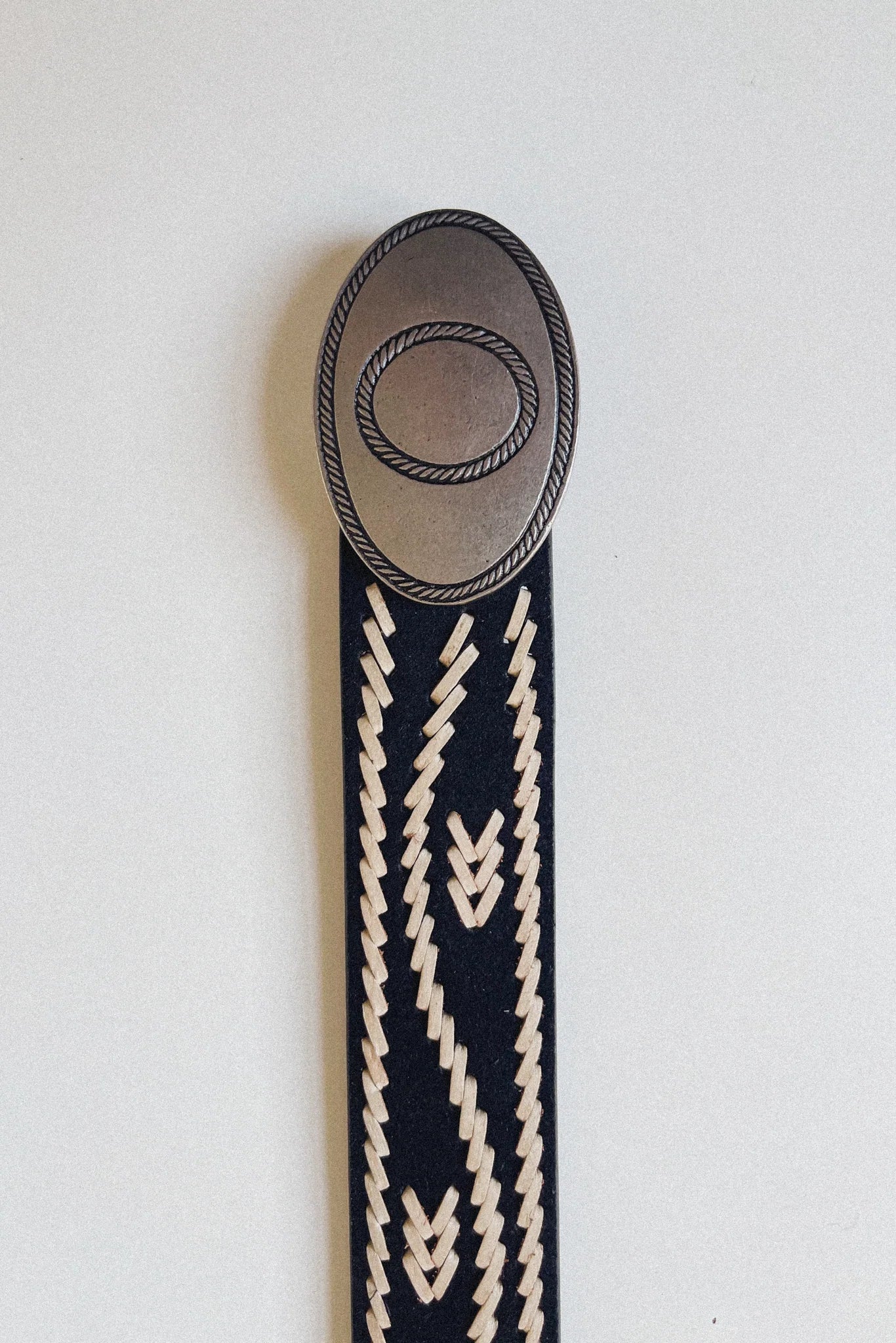 Close-up of the Malambo Belt featuring a gaucho-style oval buckle and black woven strap with cream stitching.