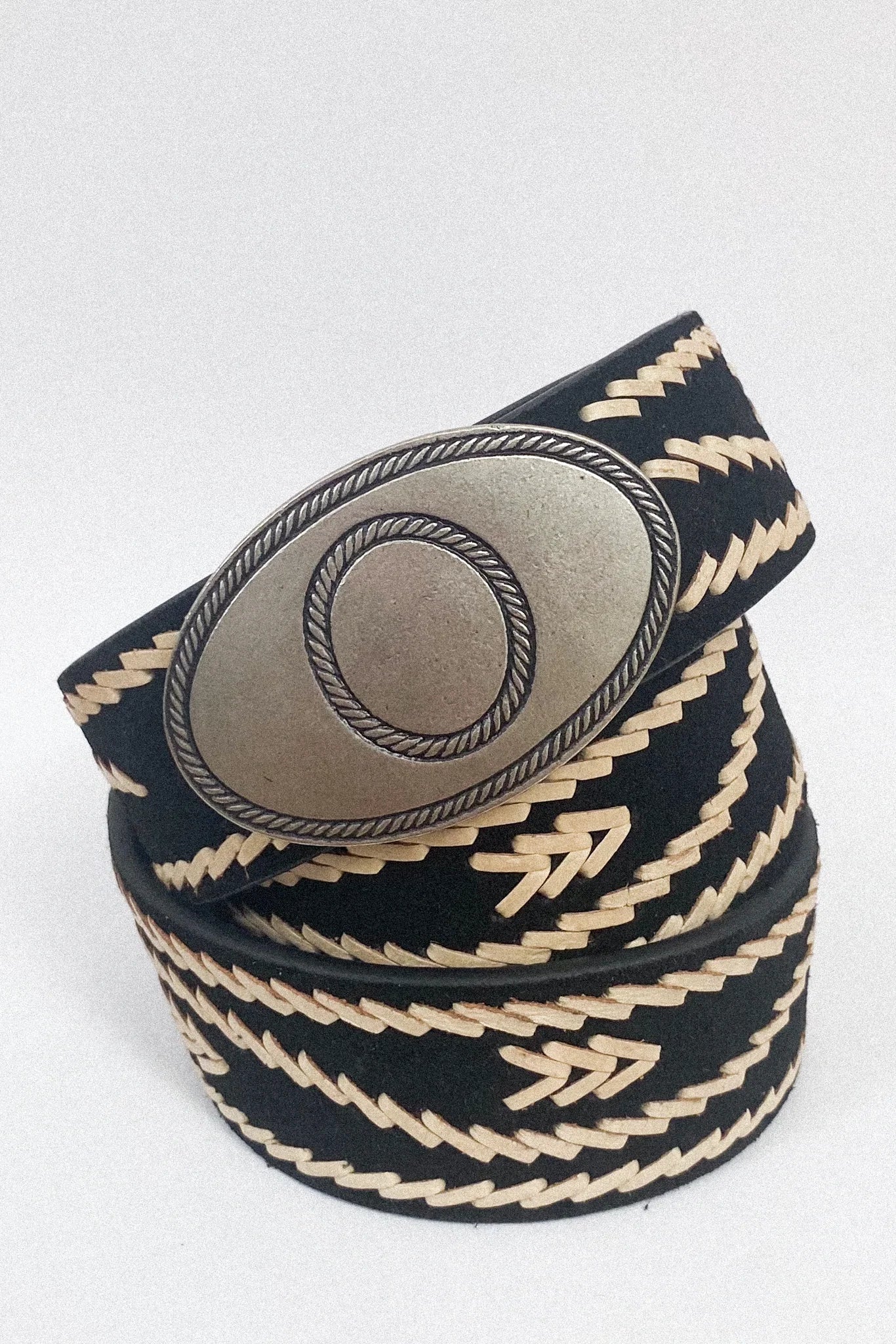 Rolled view of the Malambo Belt highlighting the black woven strap, cream stitching, and antiqued silver-tone oval buckle.