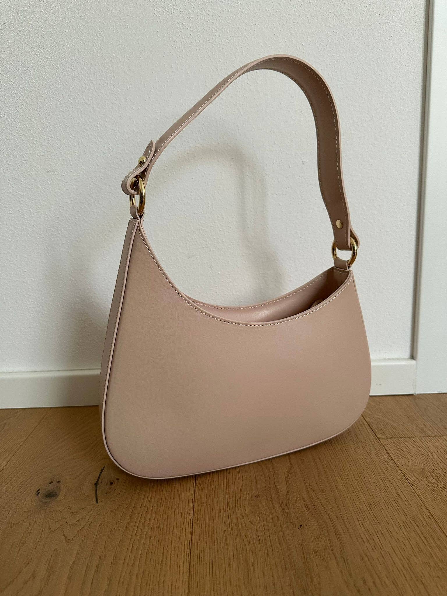 Margaret genuine leather shoulder bag in soft rose cipria featuring a curved silhouette, adjustable leather shoulder strap, gold-tone hardware, and a smooth structured finish. Made in Italy.