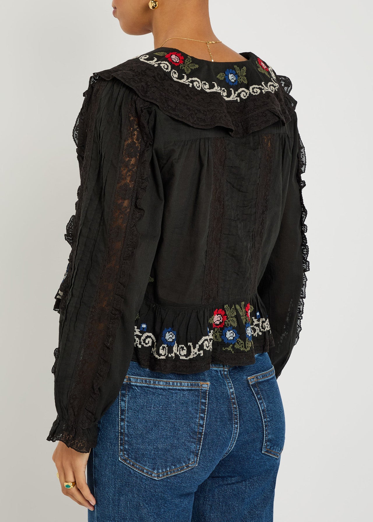 Back view of the Maribelle Top in black showcasing embroidered floral accents, lace trim, and a relaxed boho-inspired fit.