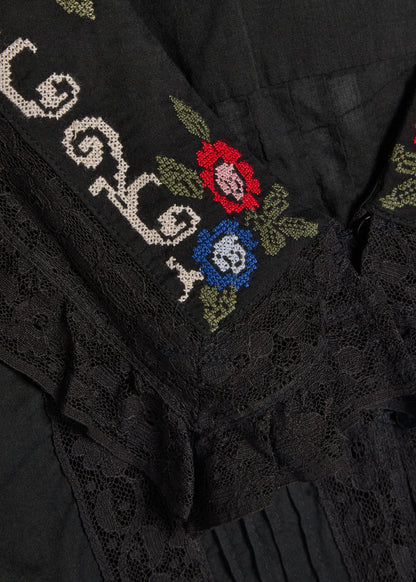 Close-up detail of the Maribelle Top showing intricate floral cross-stitch embroidery and delicate black lace trim on the neckline.
