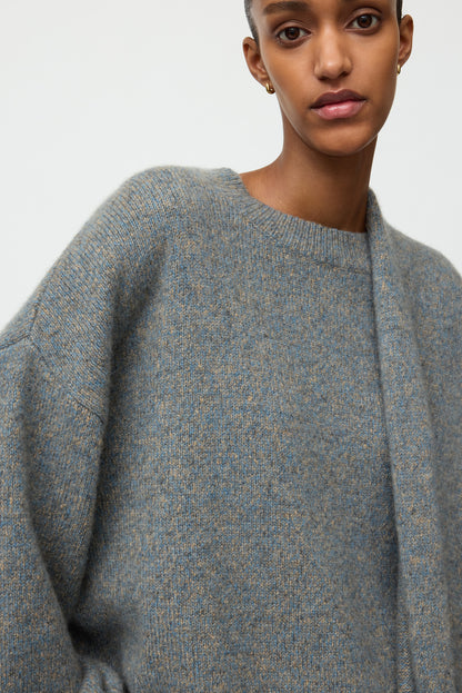 Close-up of the blue-grey marled crewneck showing its crew neckline, relaxed sleeve, and softly textured knit.