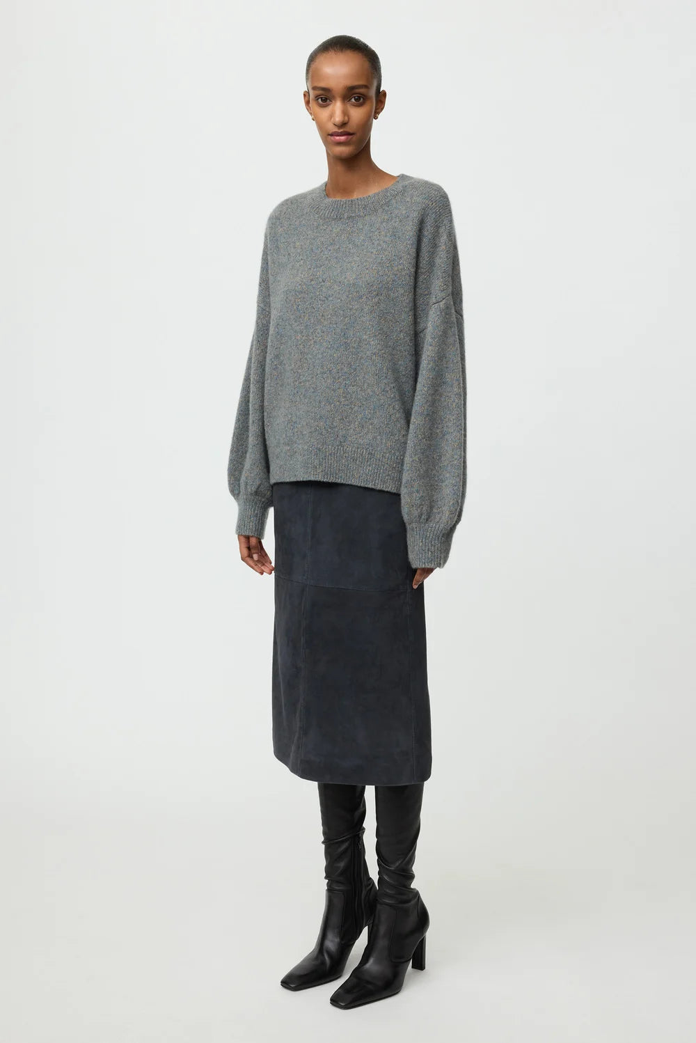 Model wearing the blue-grey marled crewneck with a dark midi skirt and black knee-high boots.