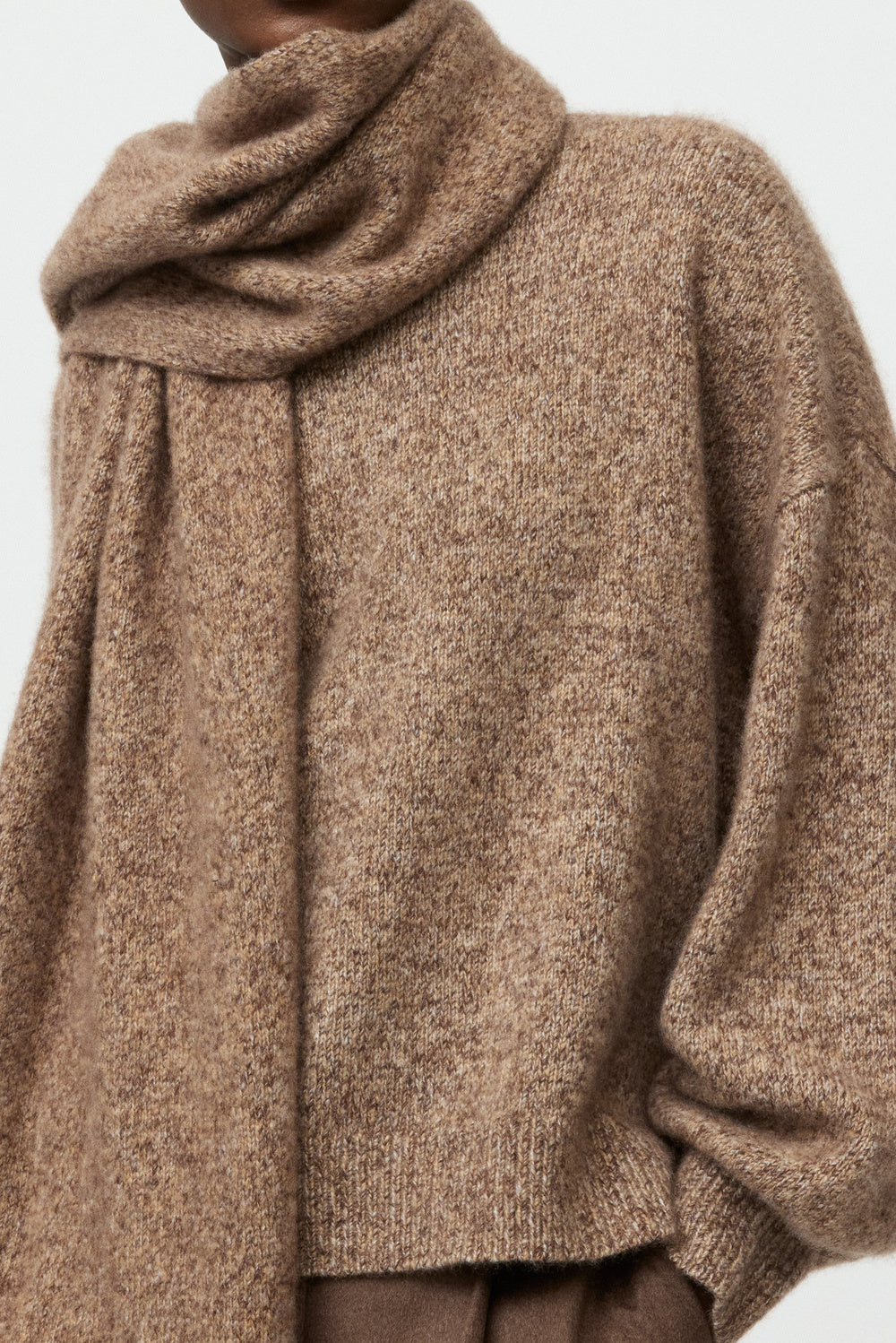Model wearing the brown melange Marled Scarf styled with a coordinating knit sweater and brown trousers.