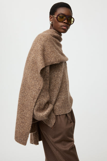 Side view of a model wearing the brown melange Marled Scarf draped over a coordinating knit sweater.