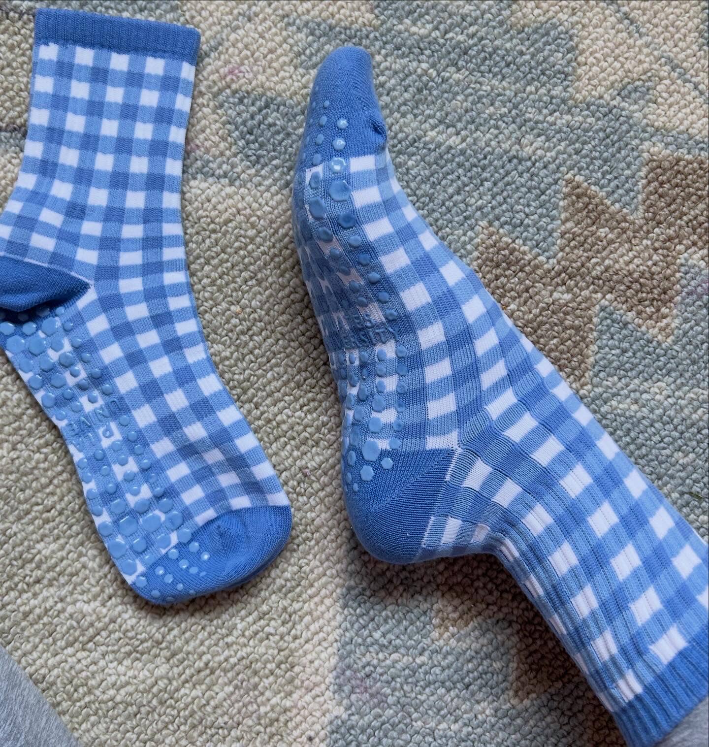 Close-up of blue and white gingham Martha's Vineyard grip socks showing the non-slip grip pattern along the sole.