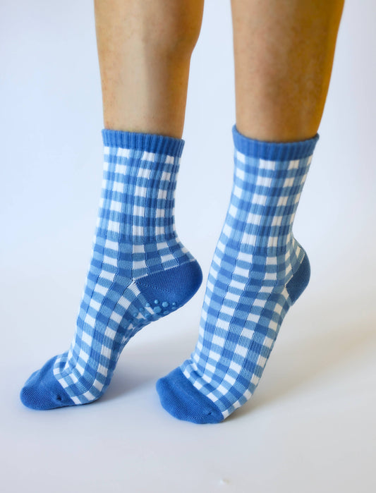 Model wearing blue and white gingham Martha's Vineyard crew socks featuring a ribbed cuff and non-slip grip sole.