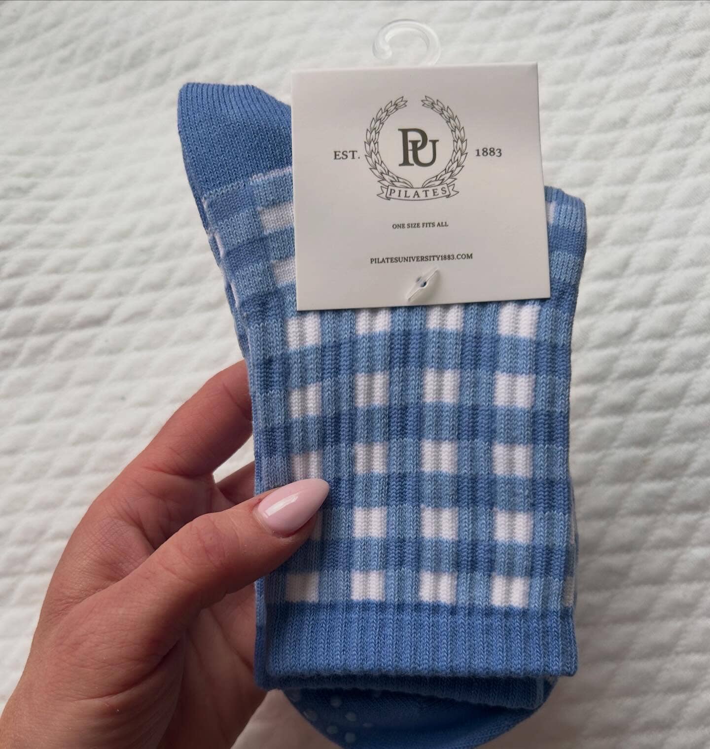 Folded pair of blue and white gingham Martha's Vineyard grip socks displayed with Pilates University branded packaging card.