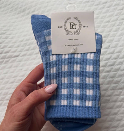 Folded pair of blue and white gingham Martha's Vineyard grip socks displayed with Pilates University branded packaging card.