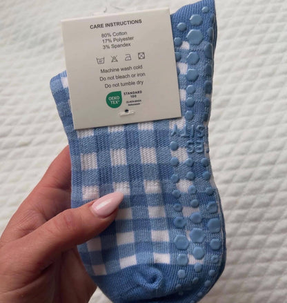 Close-up of the underside of Martha's Vineyard blue gingham grip socks showing textured non-slip grip dots and care label information.