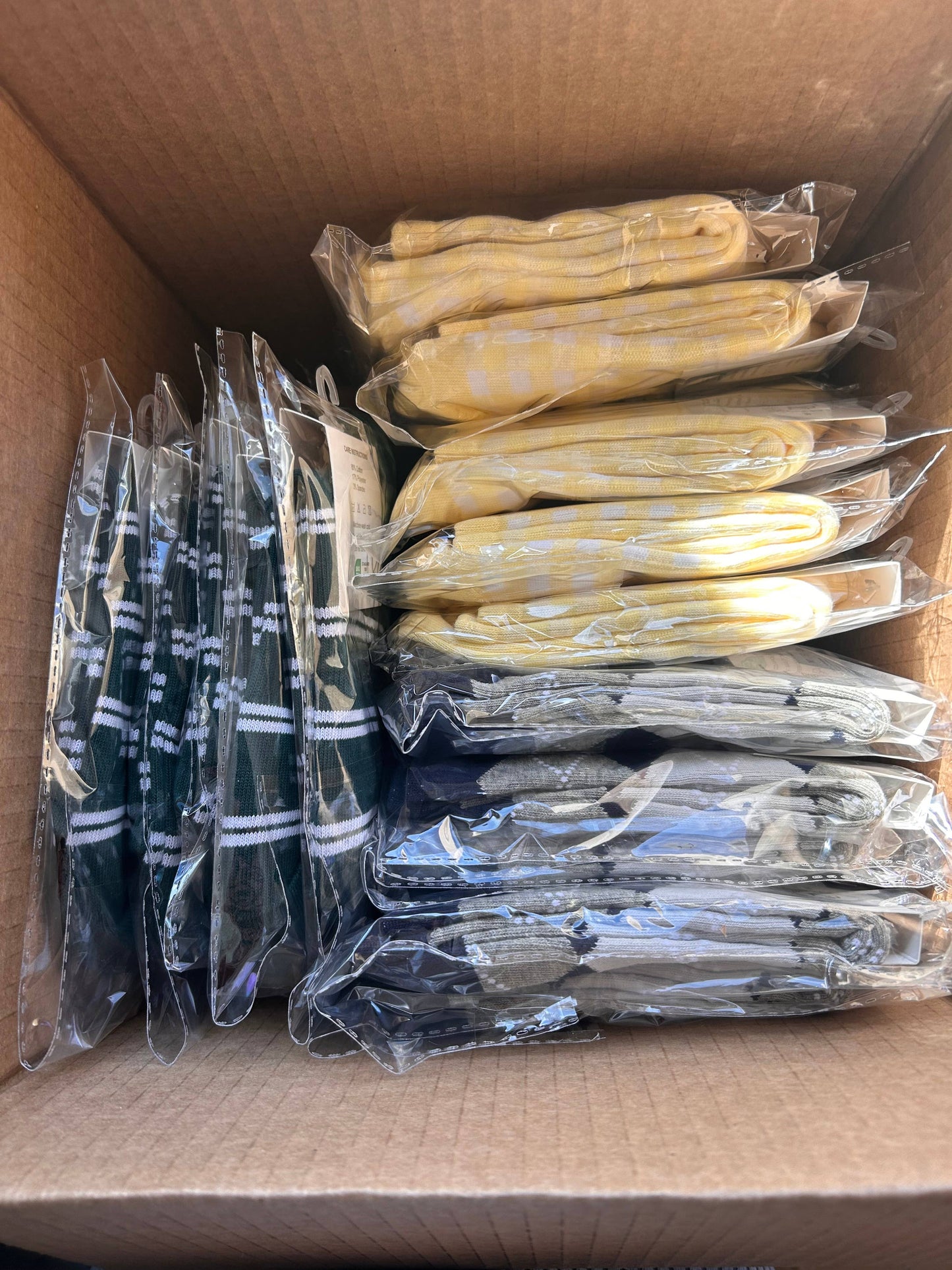Multiple pairs of Martha's Vineyard Yellow grip socks packaged individually in clear sleeves, showing the yellow and white gingham pattern and retail-ready presentation.
