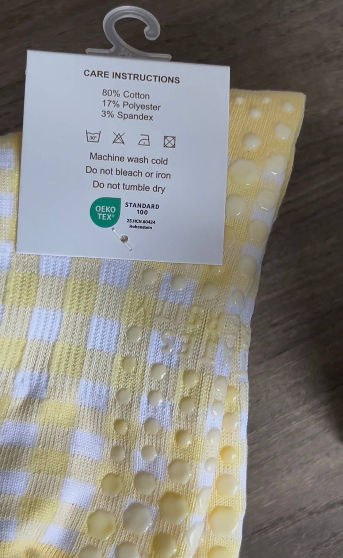 Close-up of the sole of the Martha's Vineyard Yellow grip socks featuring silicone non-slip grips, cotton-rich knit construction, and OEKO-TEX® Standard 100 certification information.