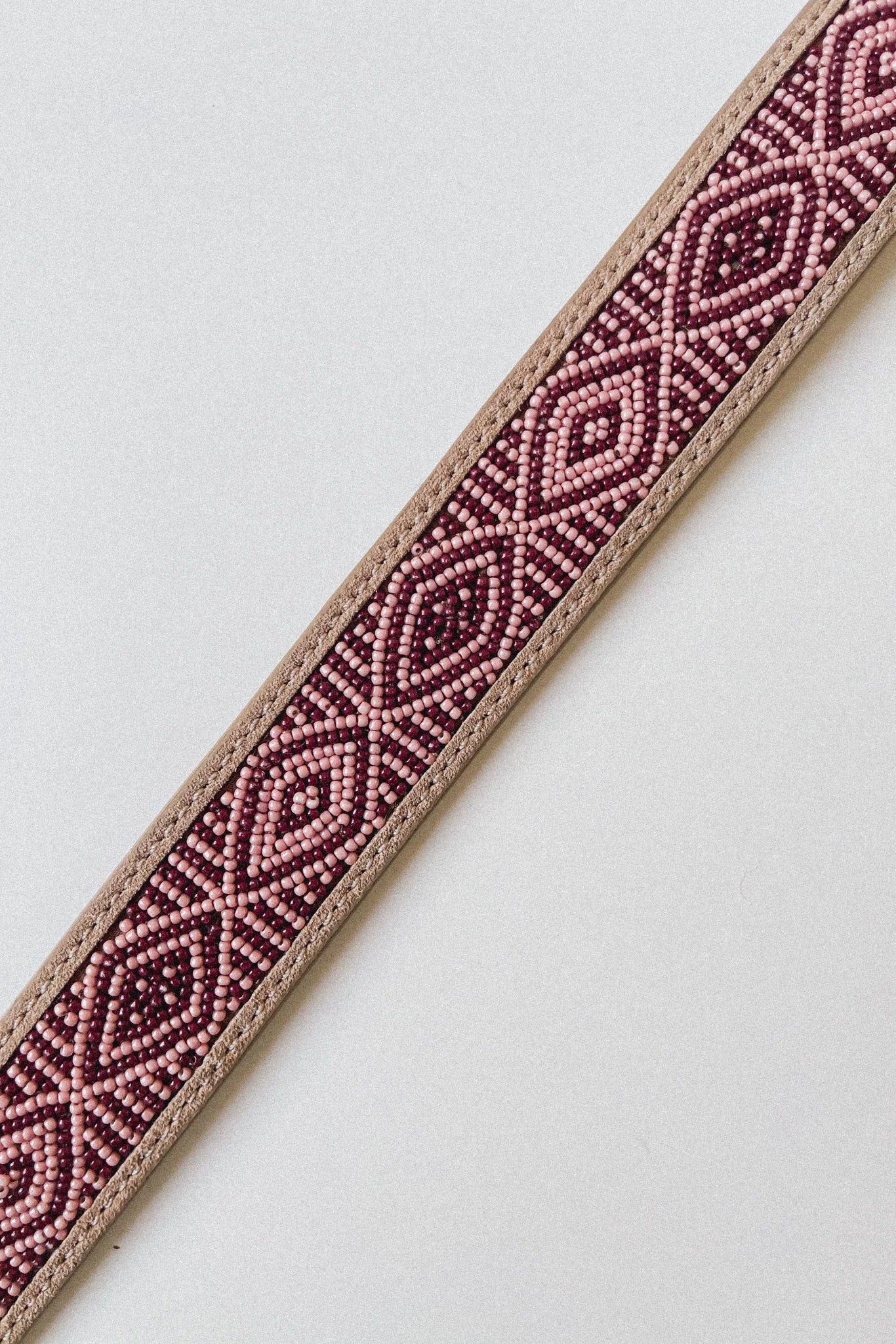 Close-up of the Masai Kilimanjaro belt with pink and burgundy geometric beadwork on leather.