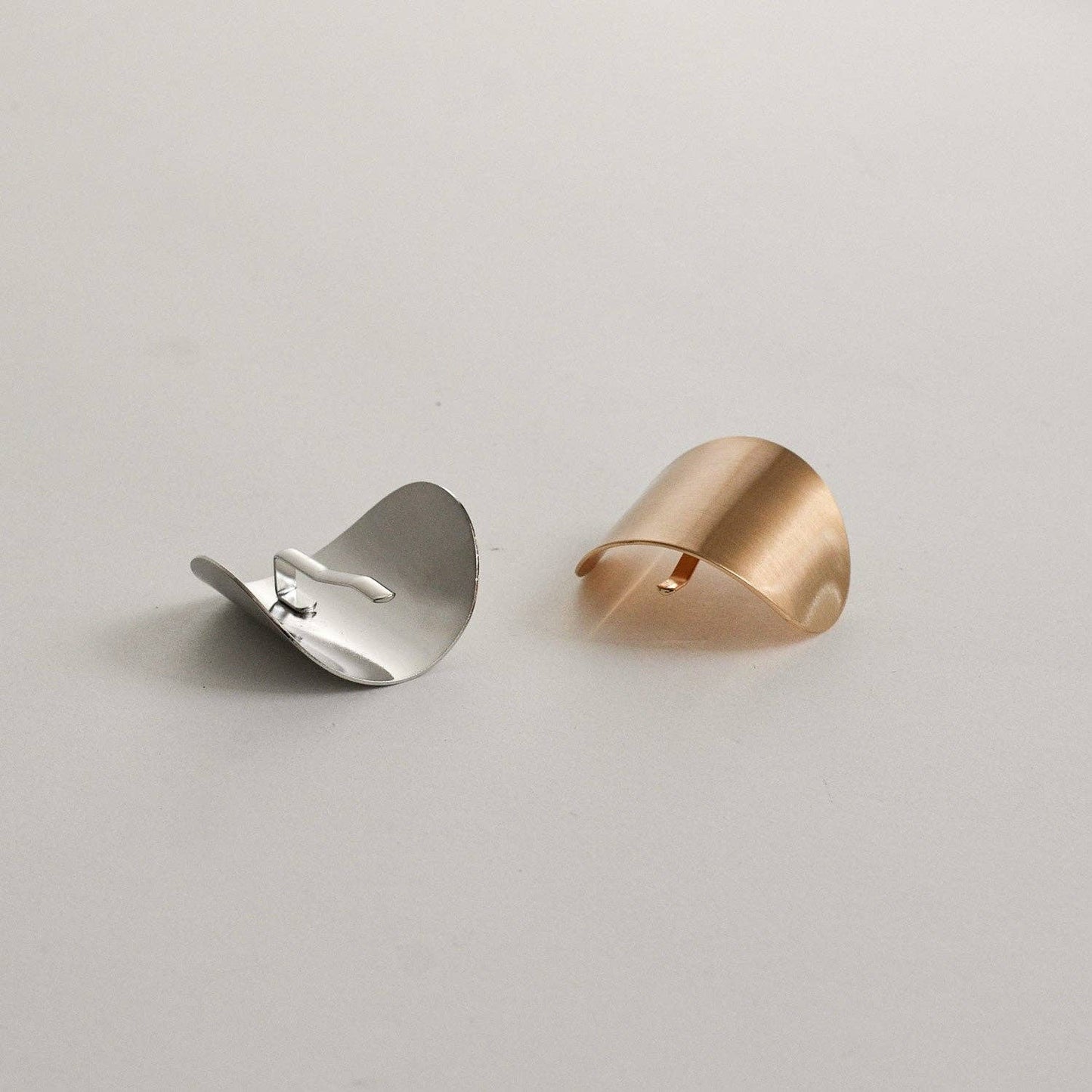 Gold and silver oval metal ponytail cuff sticks shown together on a neutral background.