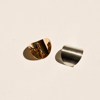 Detailed view of gold and silver oval hair cuffs showing their curved shape and reflective finish.