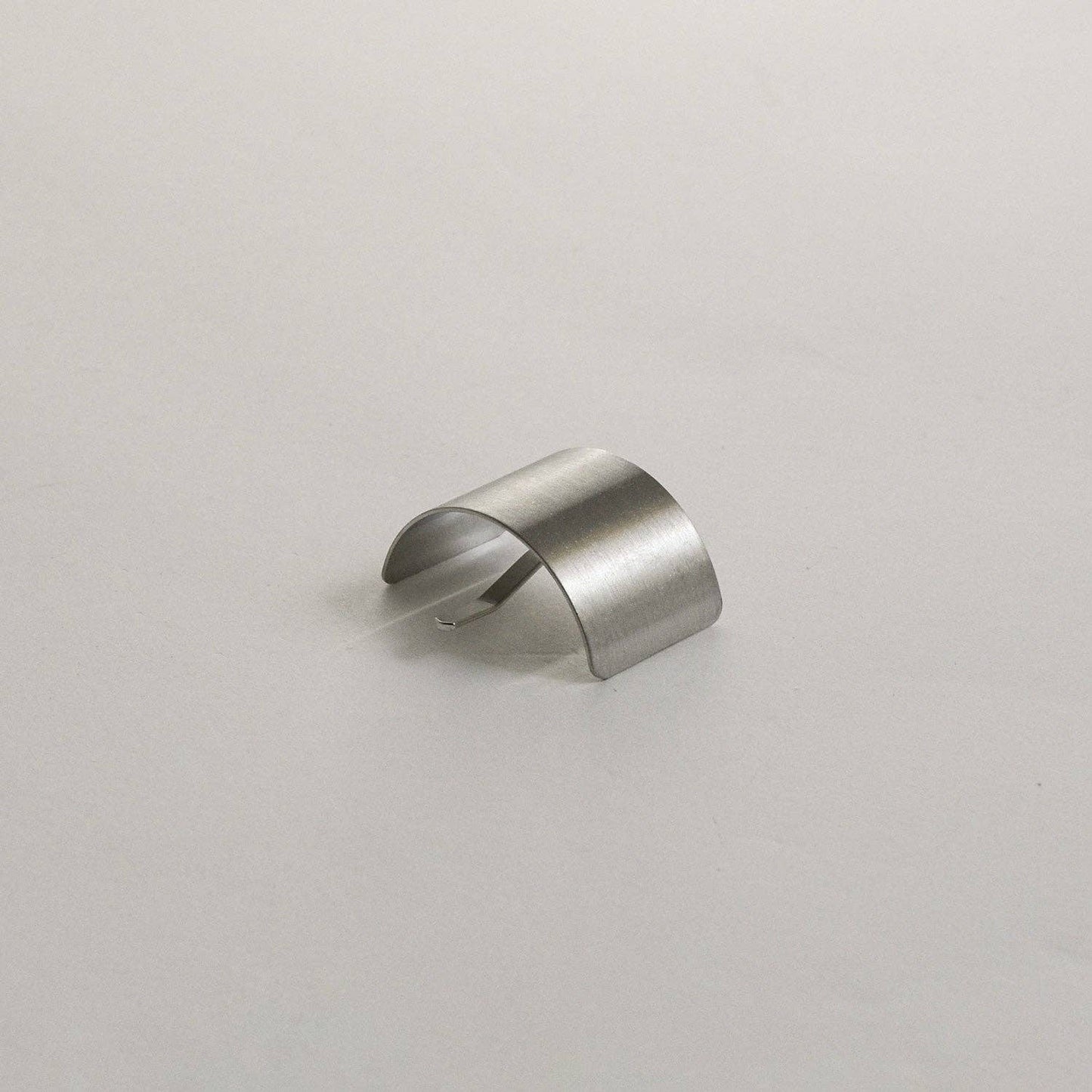 Curved profile view of the silver rectangular metal ponytail cuff stick on a neutral background.